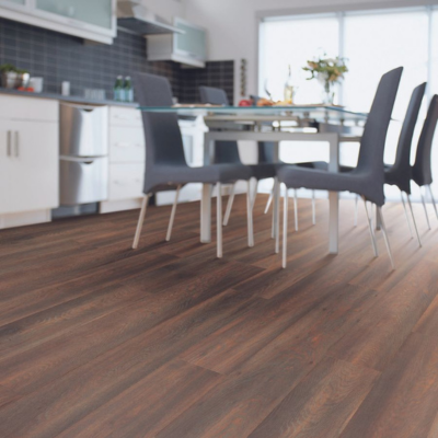 Modern dining room with dark wood laminate flooring, a glass-top dining table, and sleek gray chairs, showcasing a contemporary open-plan design.